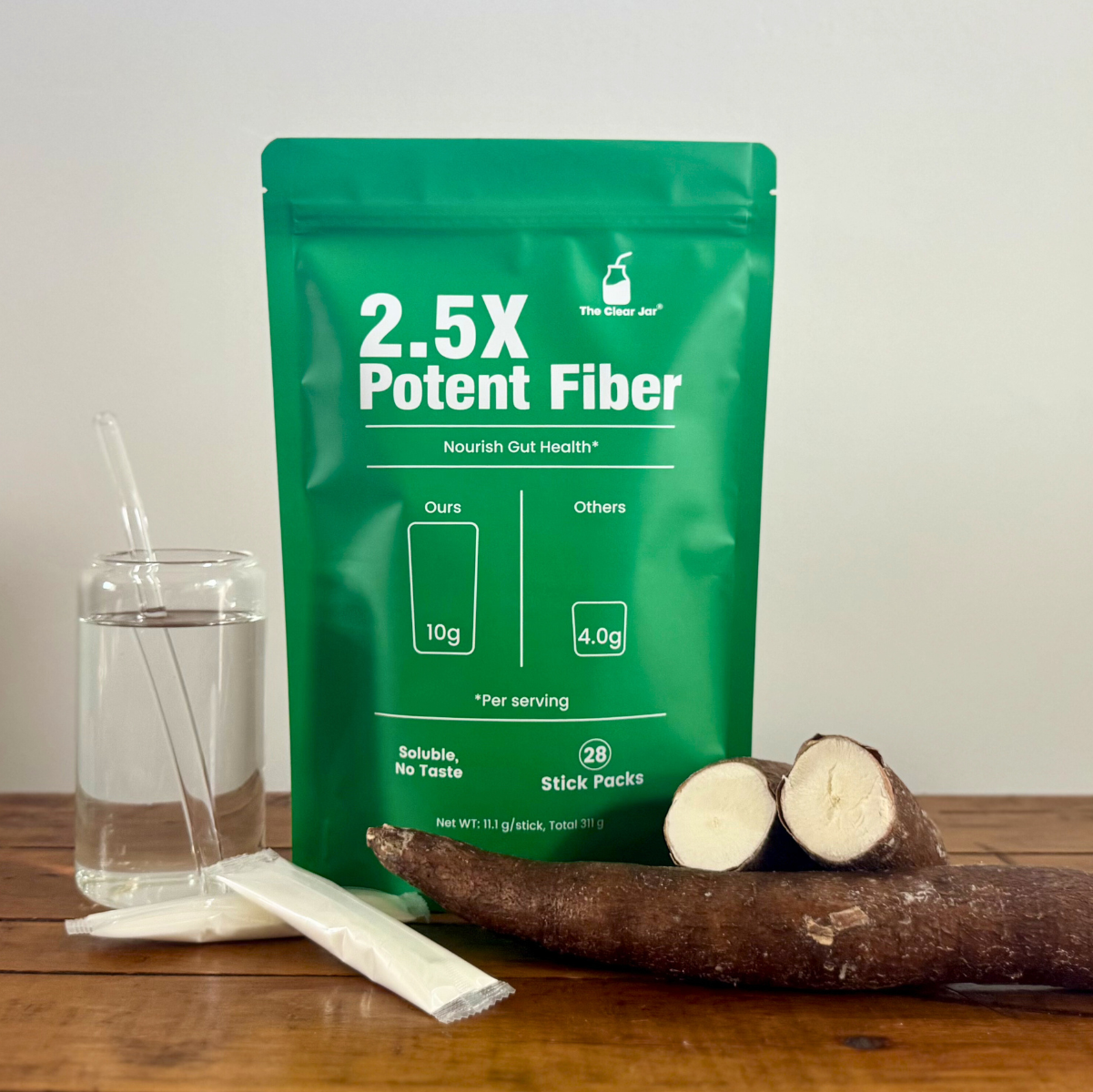 Green package of 2.5X Potent Fiber on a wooden table with a cassava root and glass of water.