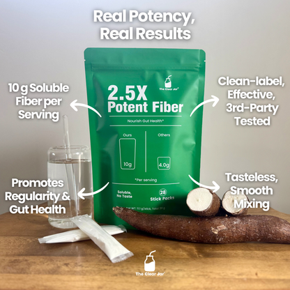 Green fiber supplement package with glass of water, fiber stick, and root on a wooden surface.
